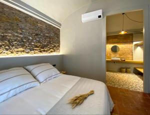 1 dormitorio con cama blanca y pared de piedra en Casa Elvira en Torroella de Montgrí
