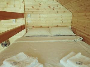 a bed in a wooden cabin with two towels at Cabana Bahna in Iloviţa