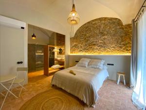 a bedroom with a bed and a stone wall at Casa Elvira in Torroella de Montgrí