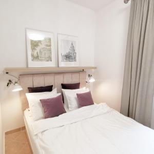 a bedroom with a bed with purple and white pillows at Hillside Apartment with AC & heating in Grande Maison in Budapest