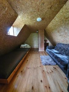 Habitación en el ático con sofá y suelo de madera. en Vēl tuvāk dabai en Kundzinisķi