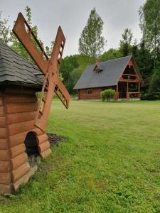 a wooden windmill in front of a log cabin at Vēl tuvāk dabai in Kundzinisķi