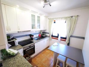 a small kitchen with white cabinets and a table at Vagueira casa férias in Aveiro