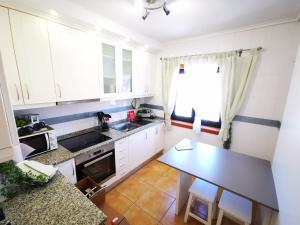 a kitchen with white cabinets and a table at Vagueira casa férias in Aveiro