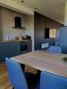 eine Küche mit einem Holztisch und blauen Stühlen in der Unterkunft Apartmán Zara in Komárno