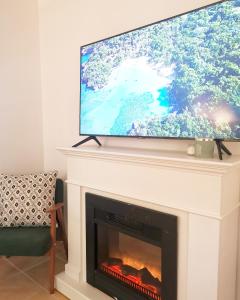a tv over a fireplace with a television on top at Hillside Apartment with AC & heating in Grande Maison in Budapest