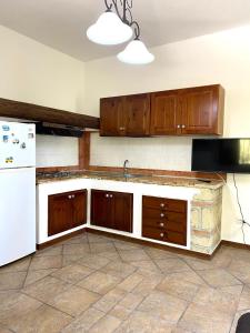 uma cozinha com armários de madeira e um frigorífico branco em Villa Lo Scoglio em Ascea