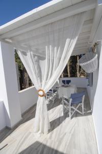 un patio con cortinas blancas y sillas azules en Kiki's apartment huge balcony dream, en Chrissi Akti