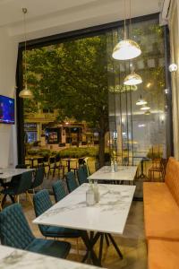 a restaurant with tables and chairs and a large window at Calla Bella Rooms & Snack Bar in Skopje