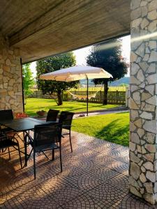 un patio con mesa y sombrilla en Corte Ohana, en Monteforte dʼAlpone
