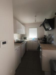 a small kitchen with white cabinets and a window at Appartement T2 accessible PMR avec terrasse et garage in Onet le Château