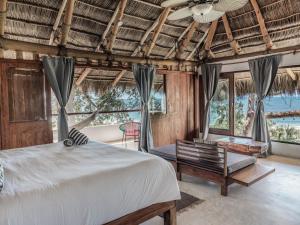 a bedroom with a bed and a bench and windows at Hotel Maraica San Pancho in San Francisco