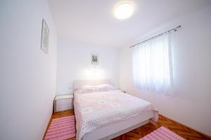 a bedroom with a bed with pink sheets and a window at Bungalows Ivan (3757) in Bol