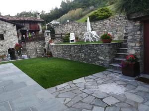 a garden with a stone wall and a lawn at Appartamento con vista chez Mary in Roisan