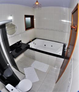 a white bathroom with a tub and a toilet at Pousada Nascer da Lua in Monte Verde