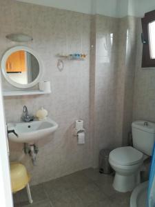 een badkamer met een wastafel, een toilet en een spiegel bij Ionos in Pyrgi Thermis