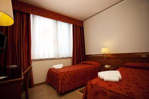 a hotel room with two beds and a window at Augustus in Ottaviano
