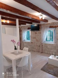 uma sala de estar com uma mesa branca e duas janelas em Studio Makala em Trogir