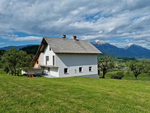 a white house on a hill with mountains in the background at M&M Apartment in Zgornje Gorje