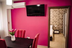 ein Esszimmer mit einer hellrosa Wand in der Unterkunft Apartment Gabriela's Home in Oradea