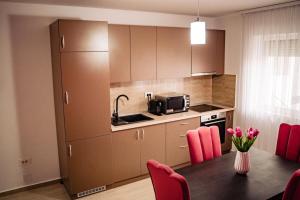 eine Küche mit einem Tisch mit rosa Stühlen und einer Mikrowelle in der Unterkunft Apartment Gabriela's Home in Oradea
