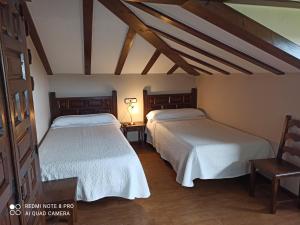 2 letti in una camera con soffitti in legno di Pension Castio a Santillana del Mar