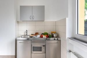 a small kitchen with a sink and a microwave at Boardinghouse Münster - das Original in Münster