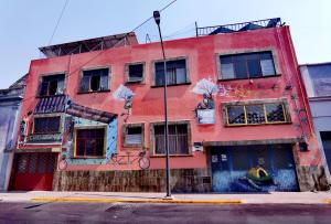 a red building with graffiti on it on a street at The Roof Backpackers in Guadalajara