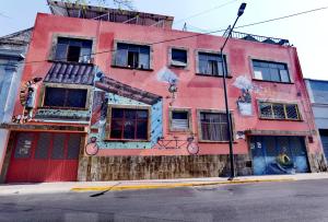ein rosafarbenes Gebäude mit Graffiti auf der Seite in der Unterkunft The Roof Backpackers in Guadalajara