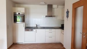 una cocina con armarios blancos y fregadero en Ferienwohnung Familie Kunz, en Friesenheim