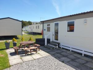 a picnic table and bench next to a trailer at 92 Barmouth Bay Holiday Park in Llanddwywe