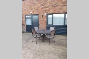 d'une terrasse avec une table, des chaises et un mur en briques. dans l'établissement Entire House - Cheshire Oaks/Ellesmere Port, à Ellesmere Port