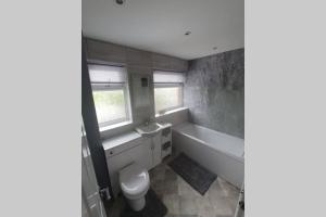 a bathroom with a tub and a toilet and a sink at Entire House - Cheshire Oaks/Ellesmere Port in Ellesmere Port