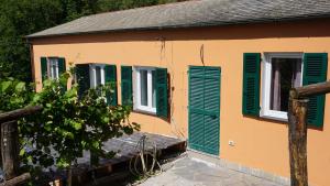 a house with green shuttered windows and a tree at Agriturismo U muinettu in La Spezia