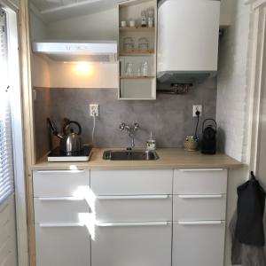 uma cozinha com armários brancos e um lavatório em Zoute Zeelucht em Katwijk aan Zee