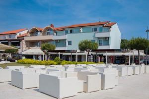 a group of white chairs in front of a building at Apartments Riva Medulin in Medulin