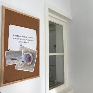uma porta com um sinal ao lado de uma janela em Zoute Zeelucht em Katwijk aan Zee