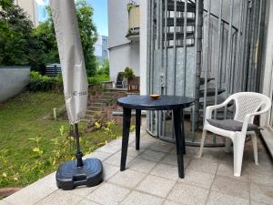 une table noire, une chaise blanche et un parasol dans l'établissement Ferienwohnung am Stötteritzer Wäldchen, à Leipzig