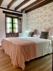- une chambre avec un grand lit et du papier peint floral dans l'établissement Apartamentos Río Cubo, à Cosgaya