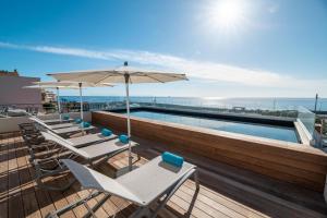 a swimming pool with chairs and an umbrella on a roof at Hotel Port Toga in Bastia