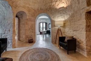 a living room with stone walls and chairs and a rug at Il Sassofono in Cisternino