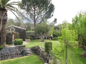 a garden with a palm tree and a stone building at Villa Vecchio in Castiglione di Sicilia