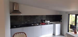 uma cozinha com armários brancos e um balcão preto em Fazenda do Sousinha no Funchal