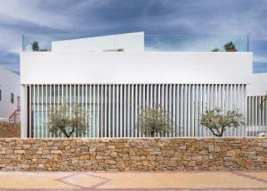 a white building with trees in front of a stone wall at Hotel Porfirio Picota - Adults Recommended in Zahara de los Atunes