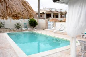 - une piscine avec des chaises et une maison dans l'établissement I Gufi Bed & Breakfast Marzamemi, à Marzamemi