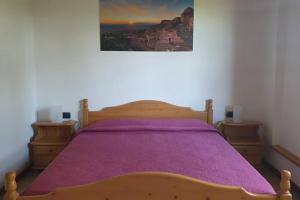 ein Schlafzimmer mit einem Holzbett mit einer lila Decke in der Unterkunft Appartamento La Rondine in Volterra