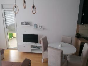 uma sala de estar com uma mesa branca e uma televisão em Emili Apartman em Jagodina