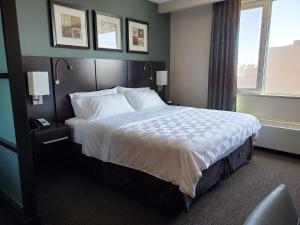 um quarto de hotel com uma cama grande com lençóis brancos em Holiday Inn Saskatoon Downtown, an IHG Hotel em Saskatoon