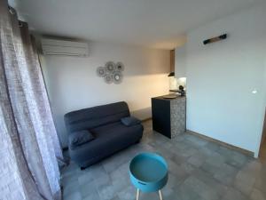 a living room with a black couch and a blue stool at Appart. F2 apercu Port de Santa Lucia St Raphaël in Saint-Raphaël