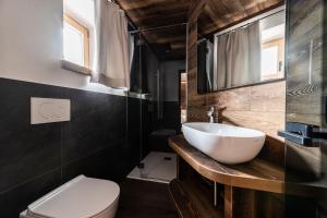 La salle de bains est pourvue d'un lavabo blanc et de toilettes. dans l'établissement ALPINE DAYS Mountain Home, à Madonna di Campiglio